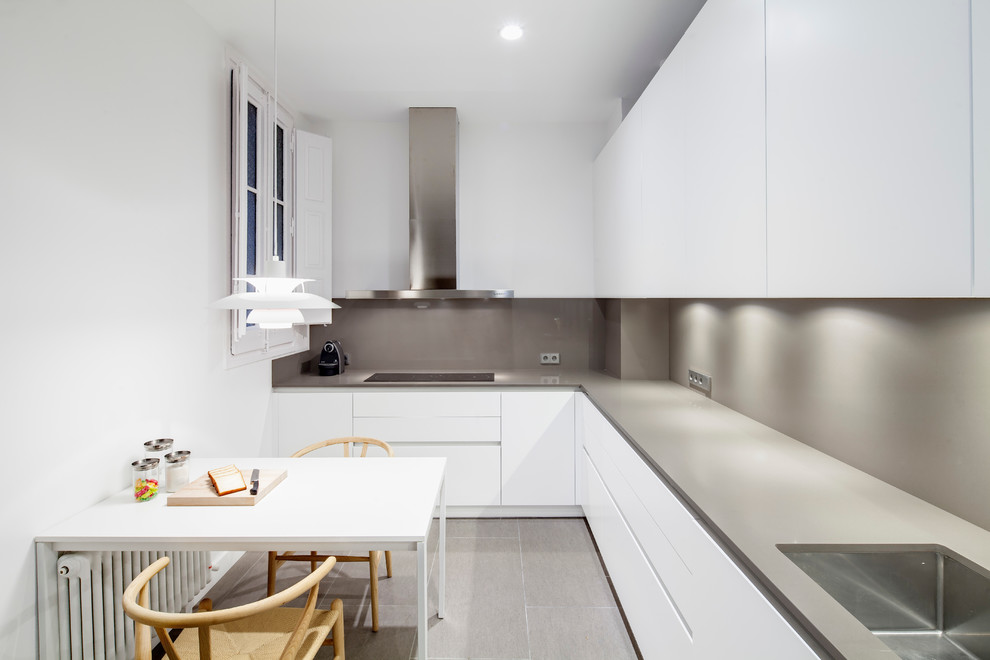 Inspiration for a mid-sized contemporary l-shaped eat-in kitchen in Barcelona with an undermount sink, flat-panel cabinets, white cabinets, solid surface benchtops, grey splashback, stainless steel appliances, ceramic floors and no island.
