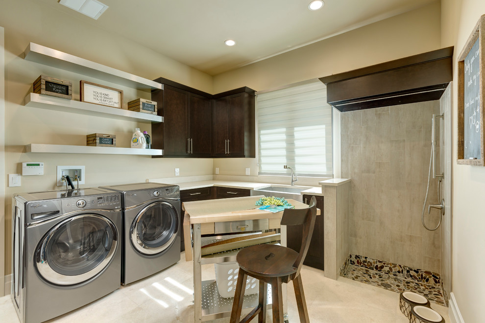 Photo of a transitional l-shaped utility room in Orlando with a farmhouse sink, shaker cabinets, dark wood cabinets, beige walls, a side-by-side washer and dryer and beige floor.