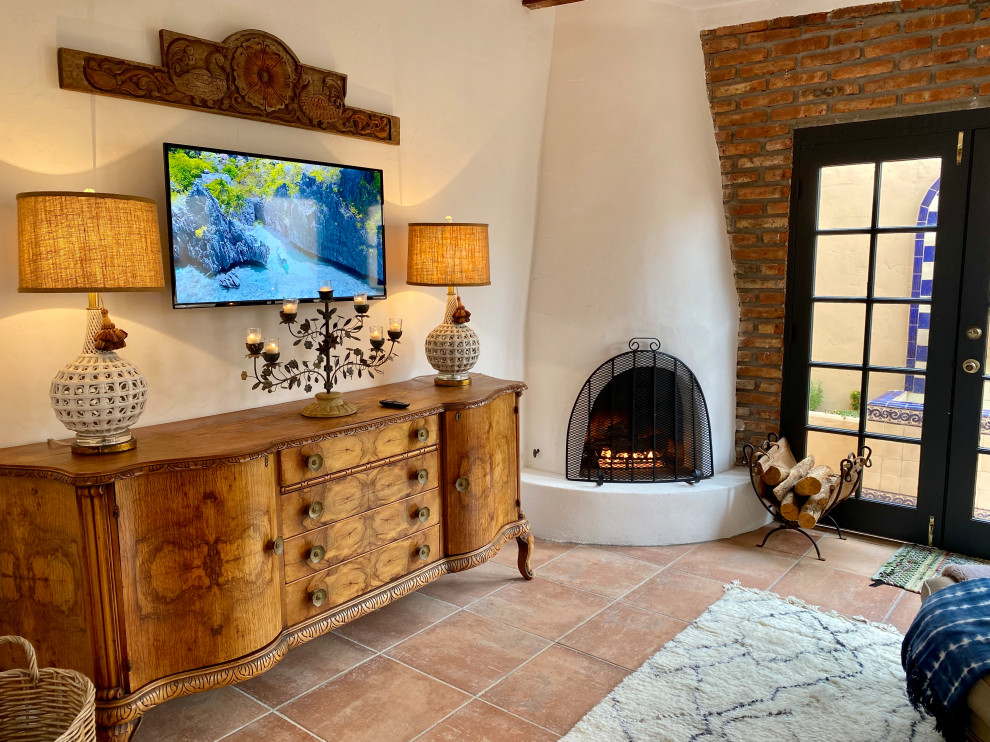 Photo of a mid-sized mediterranean open concept living room in San Diego with white walls, porcelain floors, a corner fireplace, a plaster fireplace surround, a wall-mounted tv, orange floor, exposed beam, a music area and brick walls.