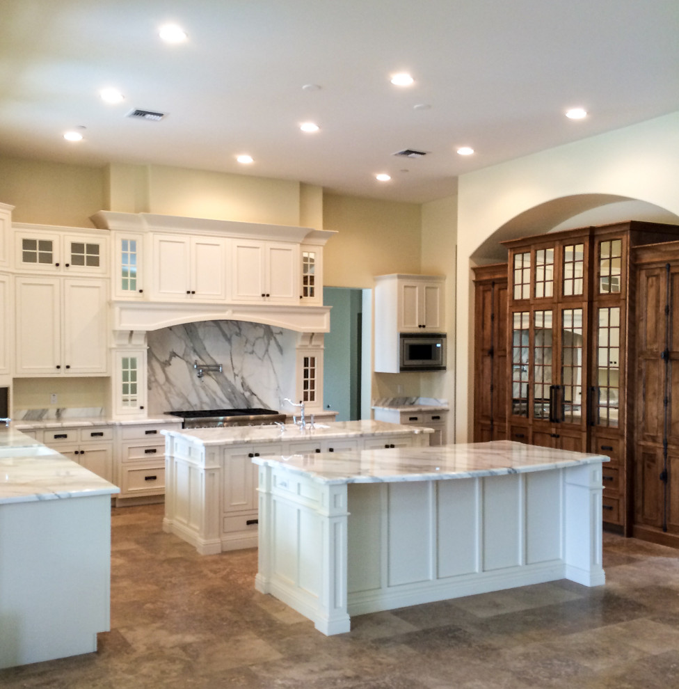Expansive transitional l-shaped eat-in kitchen in Phoenix with shaker cabinets, medium wood cabinets, granite benchtops, grey splashback, granite splashback, stainless steel appliances, multiple islands and white benchtop.