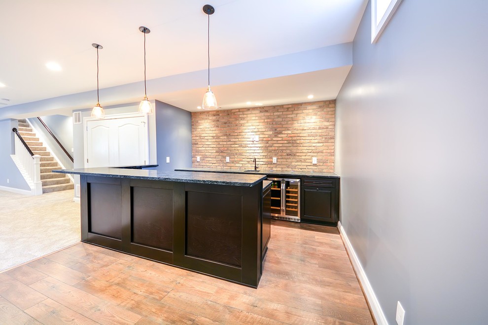 Photo of a mid-sized transitional galley wet bar in DC Metro with an undermount sink, raised-panel cabinets, black cabinets, granite benchtops, brown splashback, brick splashback, vinyl floors, brown floor and black benchtop.