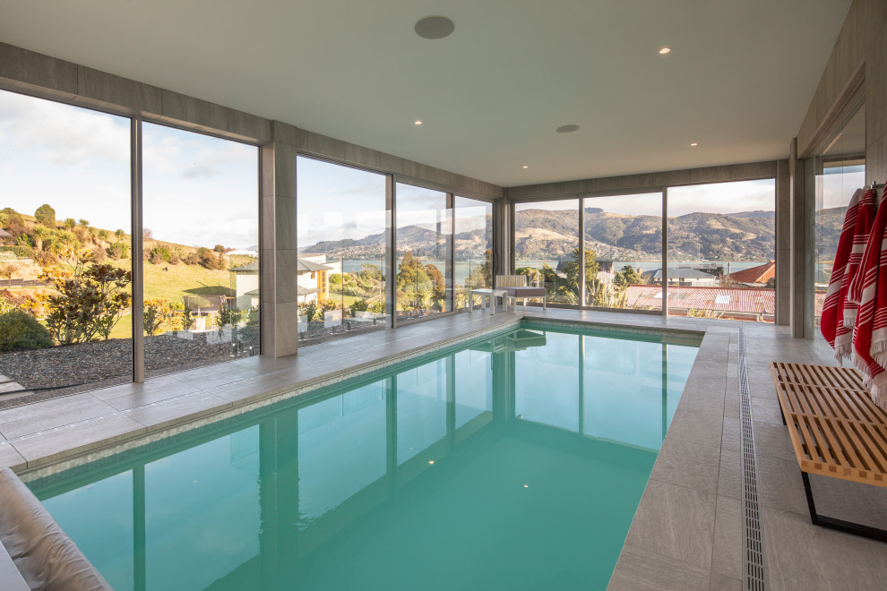 This is an example of a large modern indoor rectangular natural pool in Dunedin with a pool house.