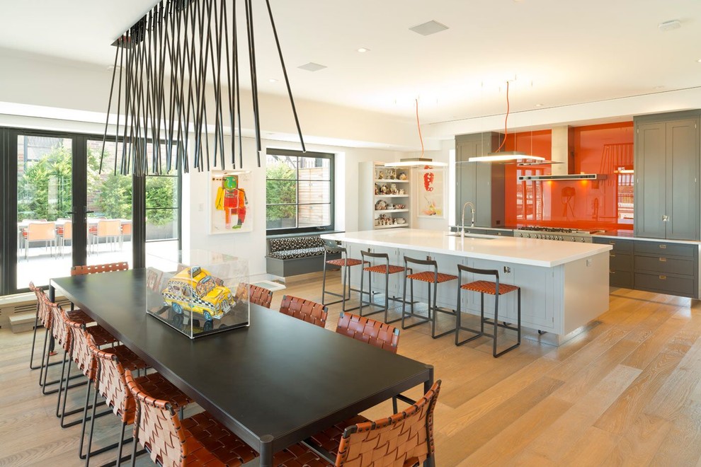 Design ideas for a large contemporary single-wall eat-in kitchen in New York with an undermount sink, shaker cabinets, grey cabinets, solid surface benchtops, orange splashback, glass tile splashback, stainless steel appliances, light hardwood floors, with island and brown floor.