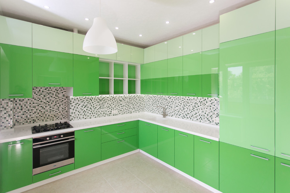 This is an example of a mid-sized contemporary l-shaped separate kitchen in Other with an undermount sink, flat-panel cabinets, green cabinets, solid surface benchtops, green splashback, mosaic tile splashback, black appliances, ceramic floors, no island and beige floor.