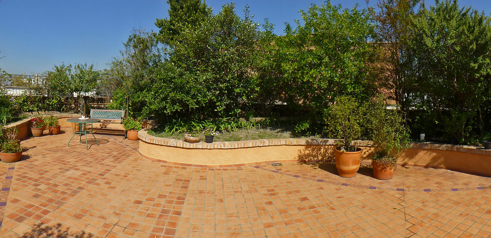 Expansive country patio in Other with tile, no cover and a container garden.