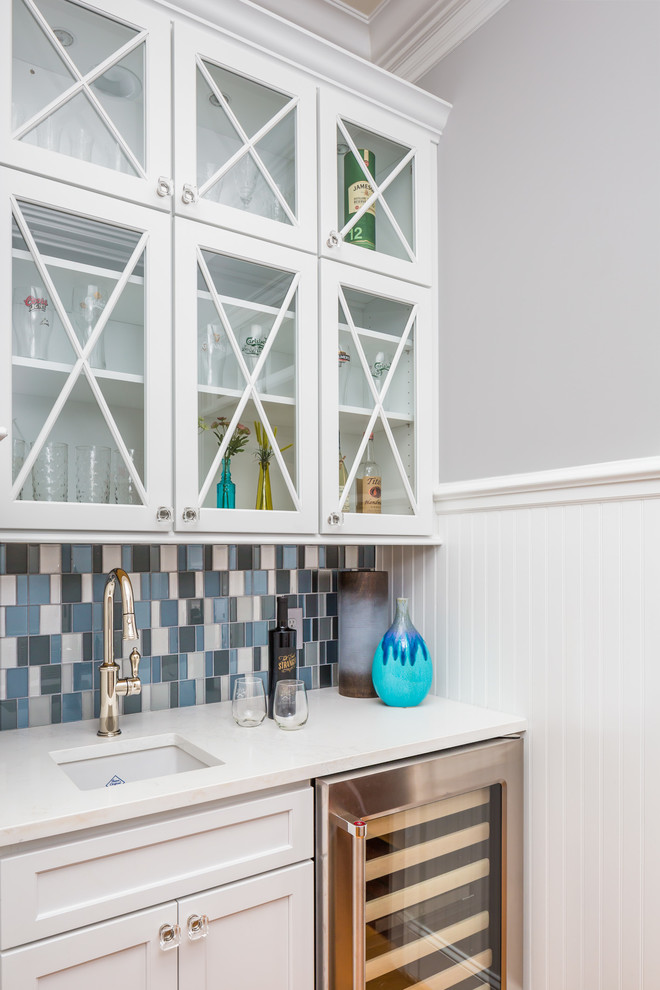 Open concept kitchen - large transitional l-shaped medium tone wood floor open concept kitchen idea in Raleigh with a farmhouse sink, flat-panel cabinets, white cabinets, quartz countertops, blue backsplash, glass tile backsplash, stainless steel appliances and an island