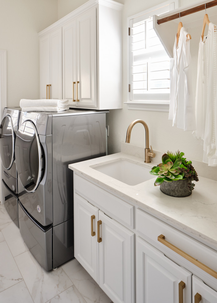 Mid-sized transitional single-wall dedicated laundry room in Austin with an undermount sink, raised-panel cabinets, white cabinets, quartz benchtops, white walls, porcelain floors, a side-by-side washer and dryer, white floor and white benchtop.