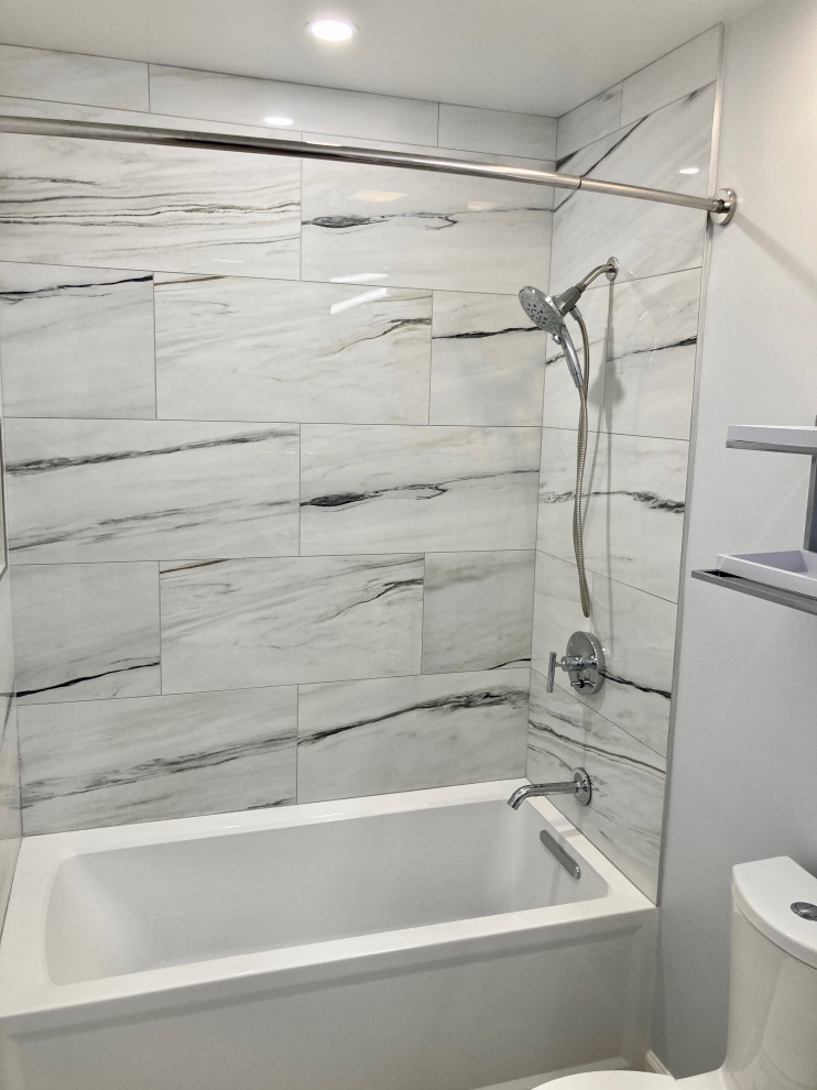 This is an example of a medium sized modern ensuite bathroom in DC Metro with flat-panel cabinets, grey cabinets, an alcove bath, an alcove shower, a two-piece toilet, white tiles, porcelain tiles, grey walls, porcelain flooring, a submerged sink, quartz worktops, grey floors, a shower curtain, white worktops, a single sink and a floating vanity unit.