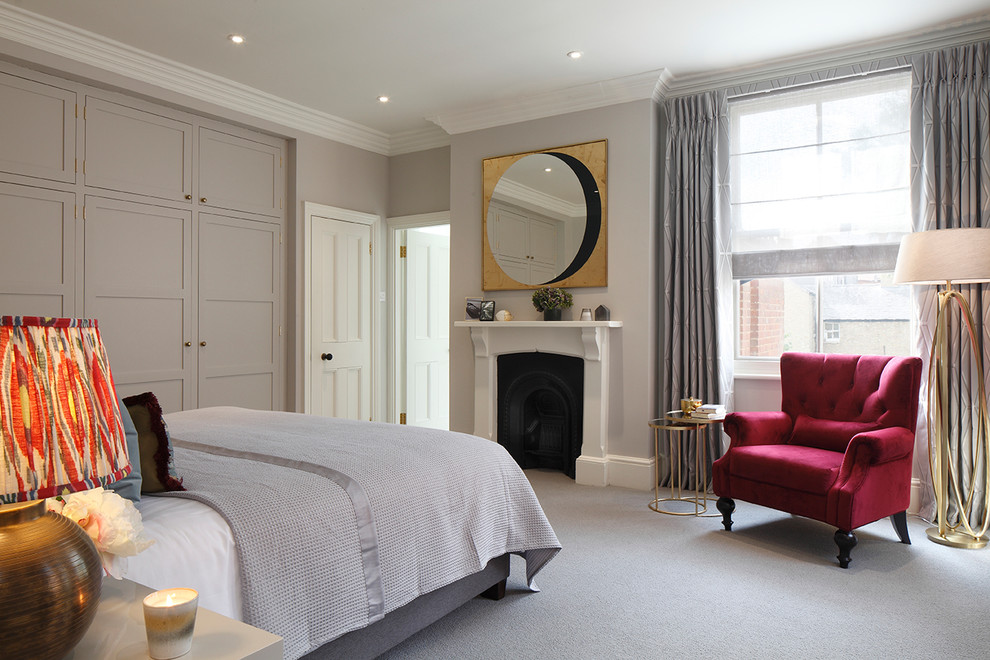 Design ideas for a large transitional master bedroom in London with grey walls, carpet, a standard fireplace, a wood fireplace surround and grey floor.