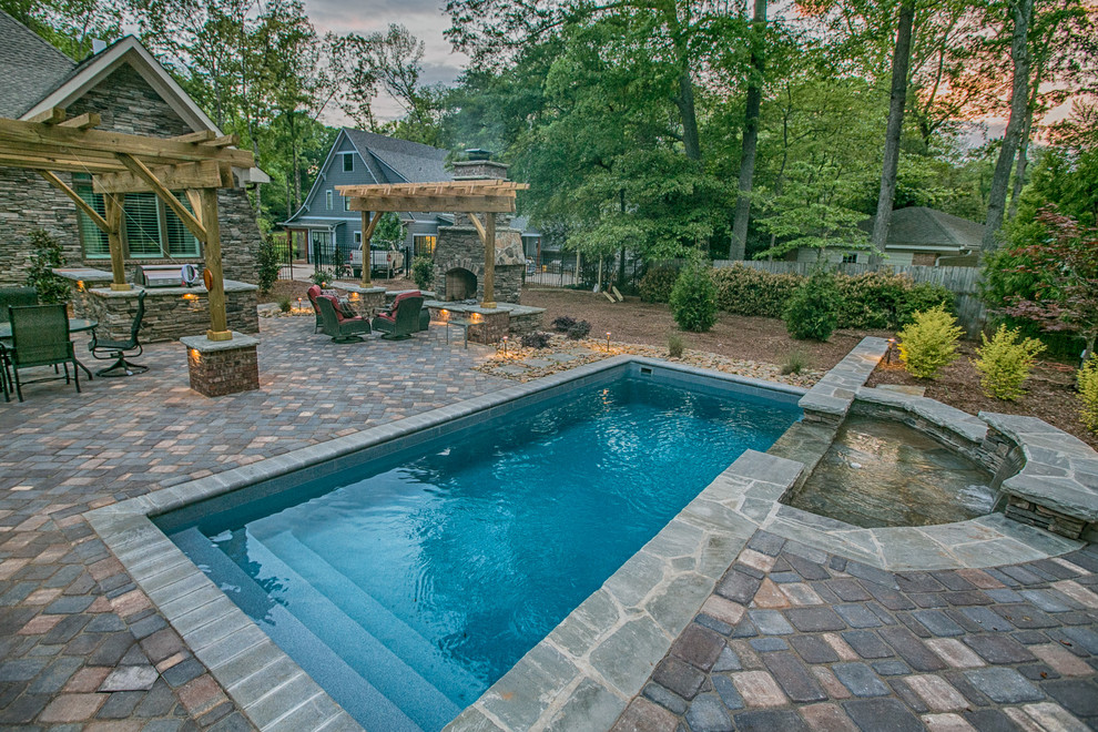 Photo of a mid-sized arts and crafts backyard rectangular lap pool in Charlotte with a water feature and concrete pavers.
