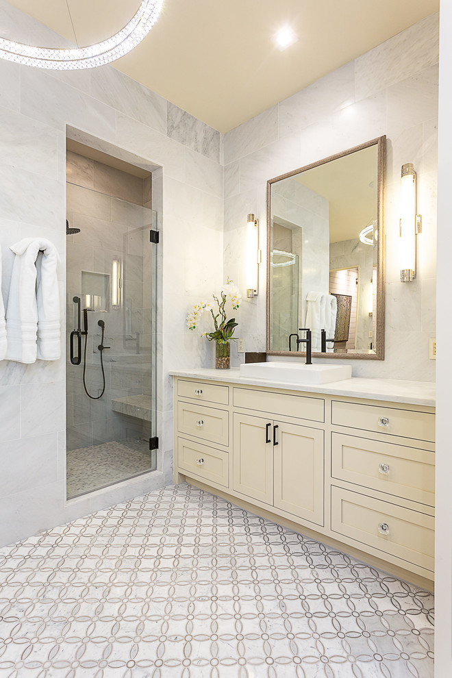 Photo of a mid-sized country master bathroom in Austin with shaker cabinets, beige cabinets, an alcove shower, gray tile, marble, grey walls, marble floors, a vessel sink, marble benchtops, grey floor, a hinged shower door and white benchtops.