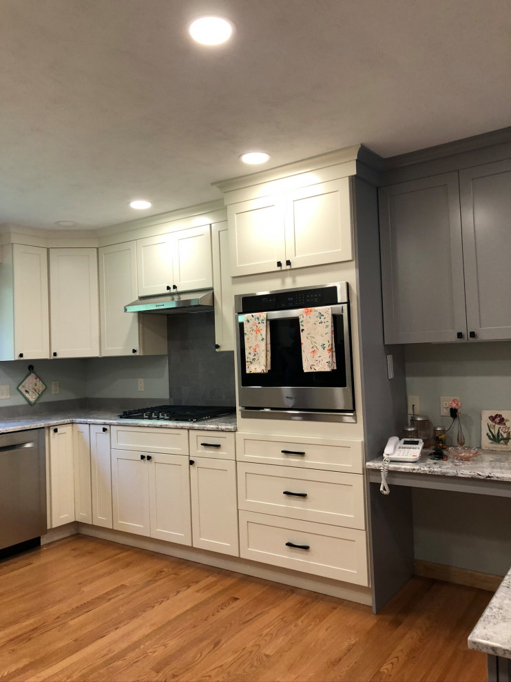 Photo of a mid-sized traditional u-shaped eat-in kitchen in Bridgeport with a single-bowl sink, shaker cabinets, white cabinets, quartz benchtops, grey splashback, ceramic splashback, stainless steel appliances, medium hardwood floors, a peninsula, brown floor and grey benchtop.