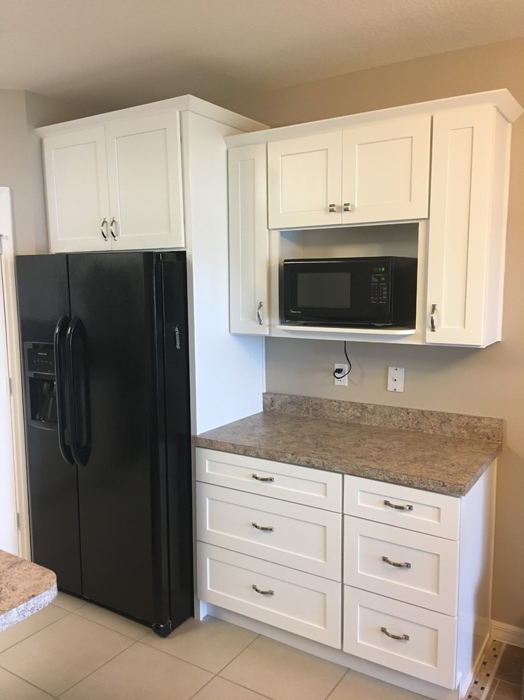 This is an example of a mid-sized transitional l-shaped eat-in kitchen in Orlando with a double-bowl sink, shaker cabinets, white cabinets, laminate benchtops, multi-coloured splashback, black appliances, ceramic floors, with island and beige floor.