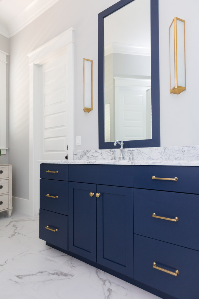 Inspiration for a mid-sized beach style master bathroom in Charleston with blue cabinets, a freestanding tub, an alcove shower, a two-piece toilet, white tile, marble, blue walls, marble floors, a vessel sink, marble benchtops, white floor, a hinged shower door, white benchtops and shaker cabinets.
