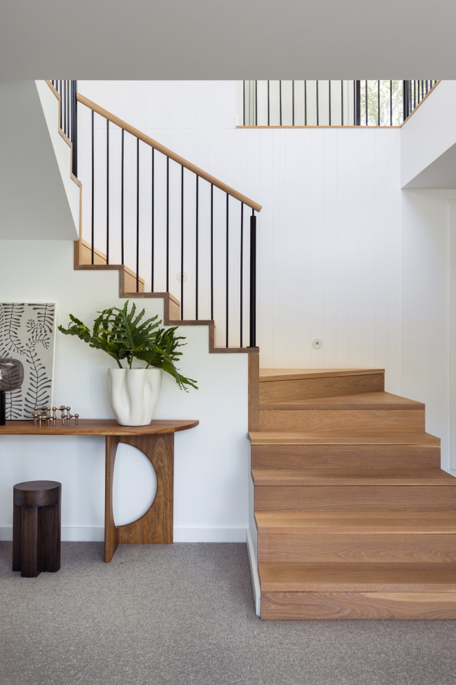 Contemporary wood u-shaped staircase in Sydney with wood risers, metal railing and decorative wall panelling.