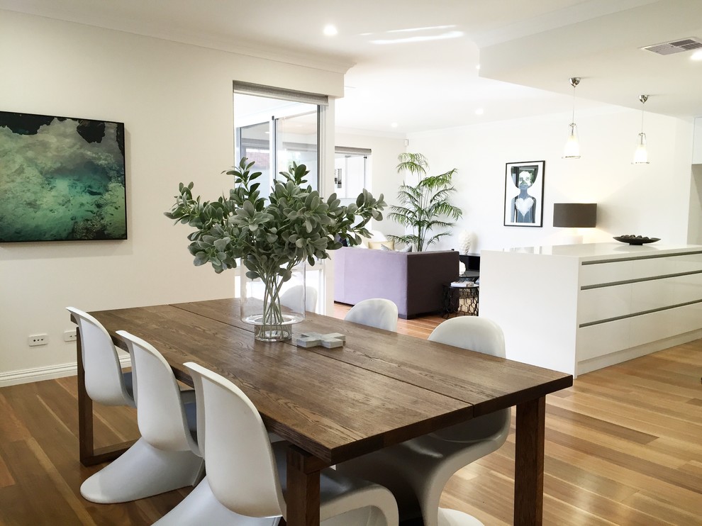 Contemporary open plan dining in Perth with white walls and light hardwood floors.