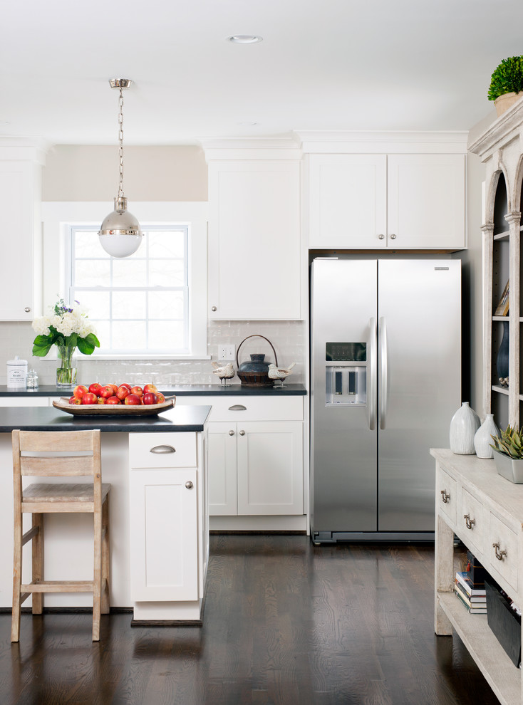 Inspiration for a mid-sized transitional l-shaped eat-in kitchen in DC Metro with a farmhouse sink, shaker cabinets, white cabinets, granite benchtops, subway tile splashback, stainless steel appliances, dark hardwood floors, with island and beige splashback.