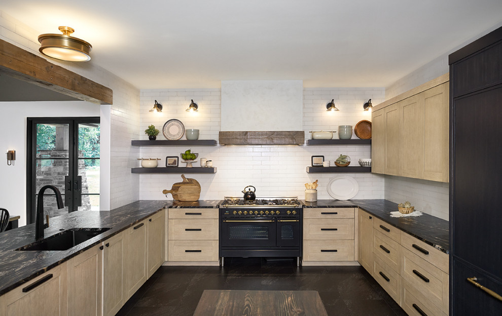 Design ideas for a country u-shaped eat-in kitchen in Grand Rapids with an undermount sink, recessed-panel cabinets, light wood cabinets, granite benchtops, white splashback, subway tile splashback, panelled appliances, with island, black floor and black benchtop.