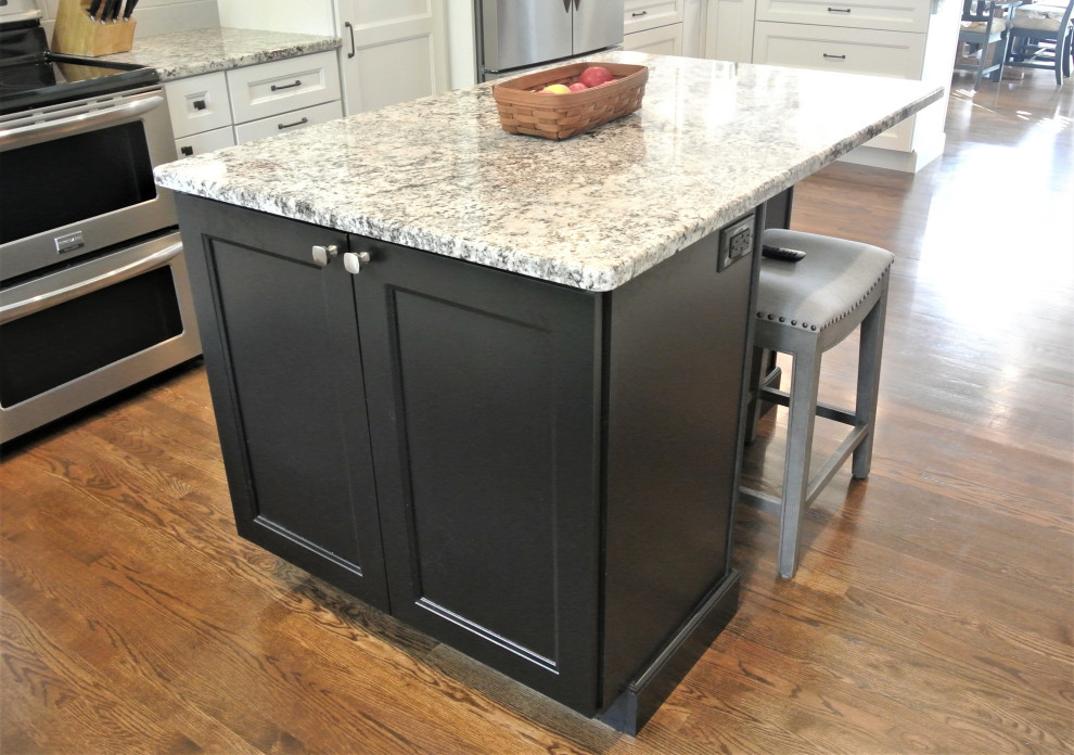 Inspiration for a transitional l-shaped medium tone wood floor and brown floor eat-in kitchen remodel in Boston with an undermount sink, shaker cabinets, white cabinets, granite countertops, beige backsplash, subway tile backsplash, stainless steel appliances, an island and beige countertops