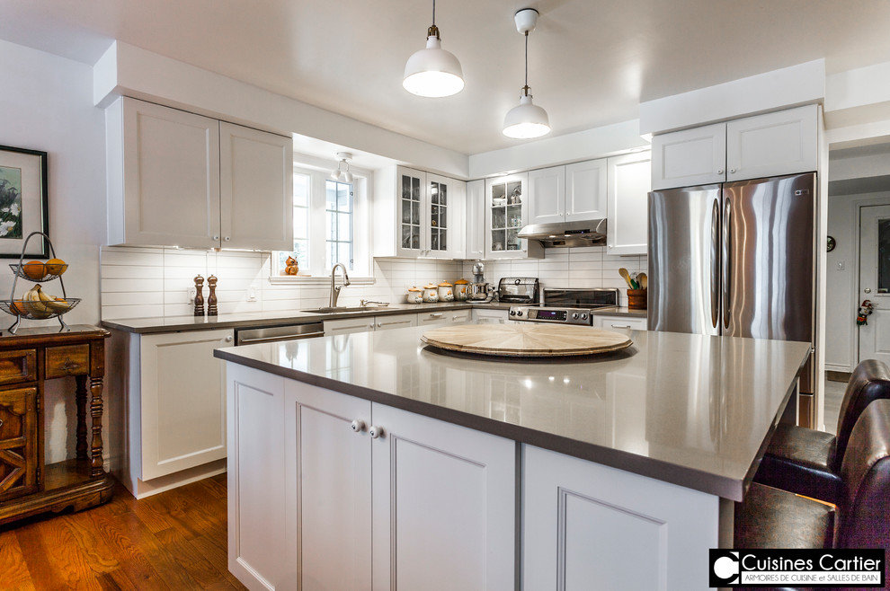 Inspiration for a large transitional medium tone wood floor eat-in kitchen remodel in Montreal with a double-bowl sink, shaker cabinets, white cabinets, quartzite countertops, white backsplash, ceramic backsplash, stainless steel appliances and an island