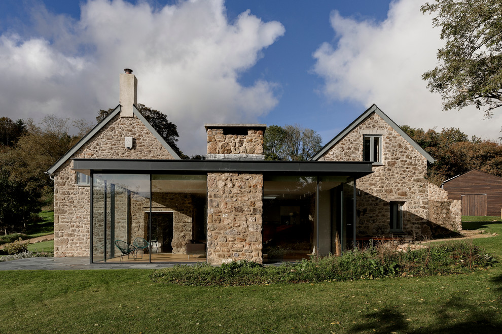 Design ideas for a large two-storey exterior in Devon with stone veneer and a flat roof.