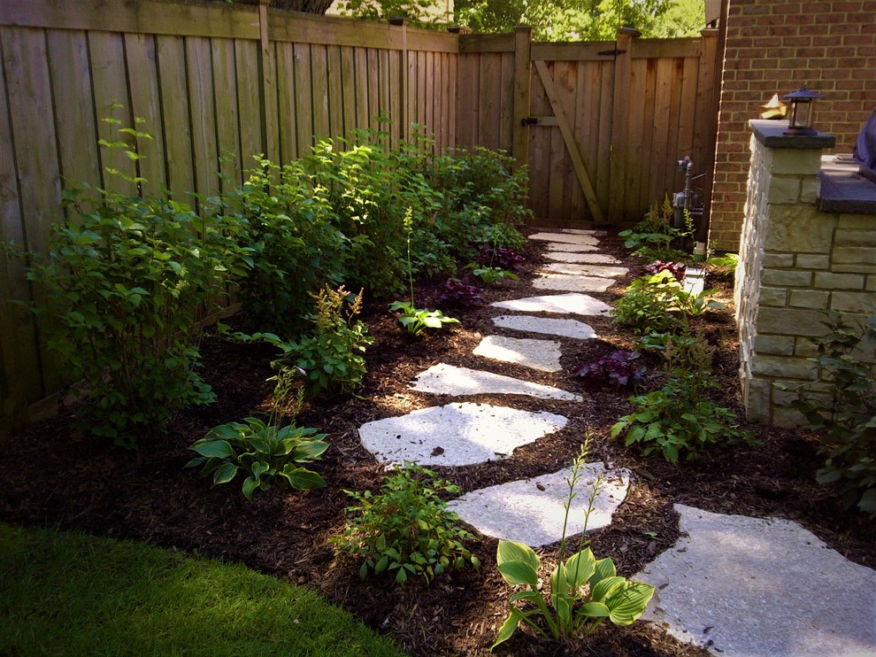 Photo of a small traditional backyard shaded formal garden for summer in Chicago with a garden path and natural stone pavers.
