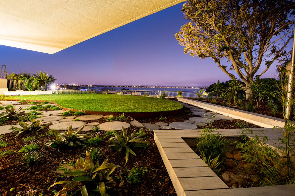 This is an example of a contemporary backyard xeriscape in Perth with decking and with lawn edging.