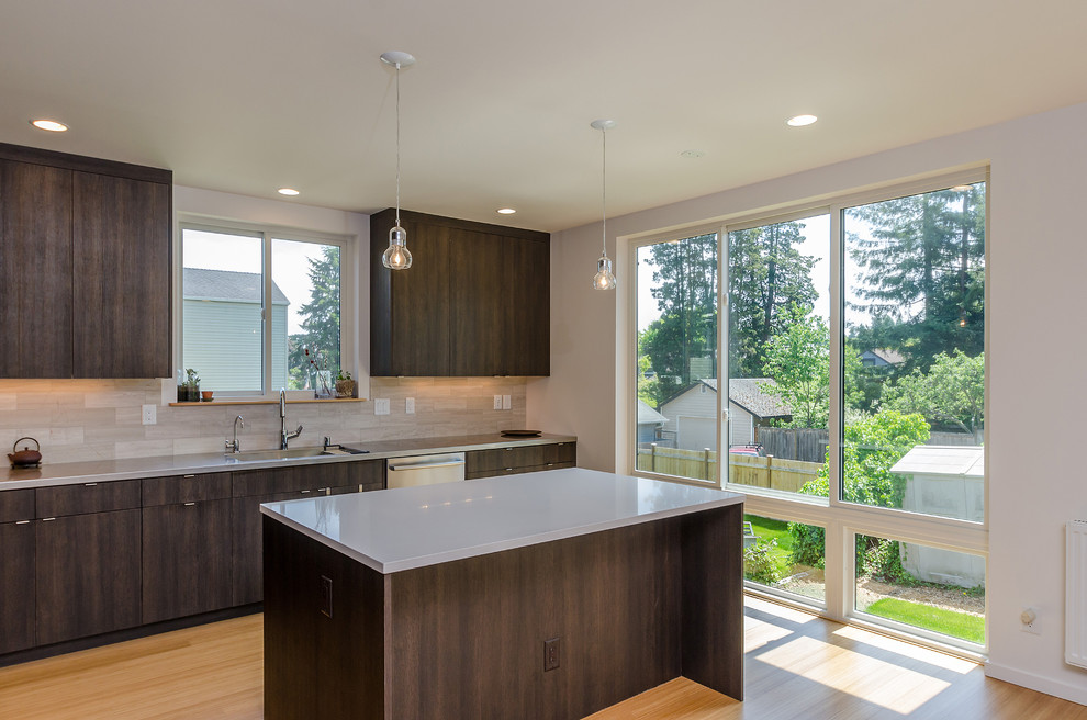 Mid-sized modern l-shaped open plan kitchen in Seattle with an integrated sink, flat-panel cabinets, dark wood cabinets, quartz benchtops, beige splashback, porcelain splashback, stainless steel appliances, bamboo floors and with island.