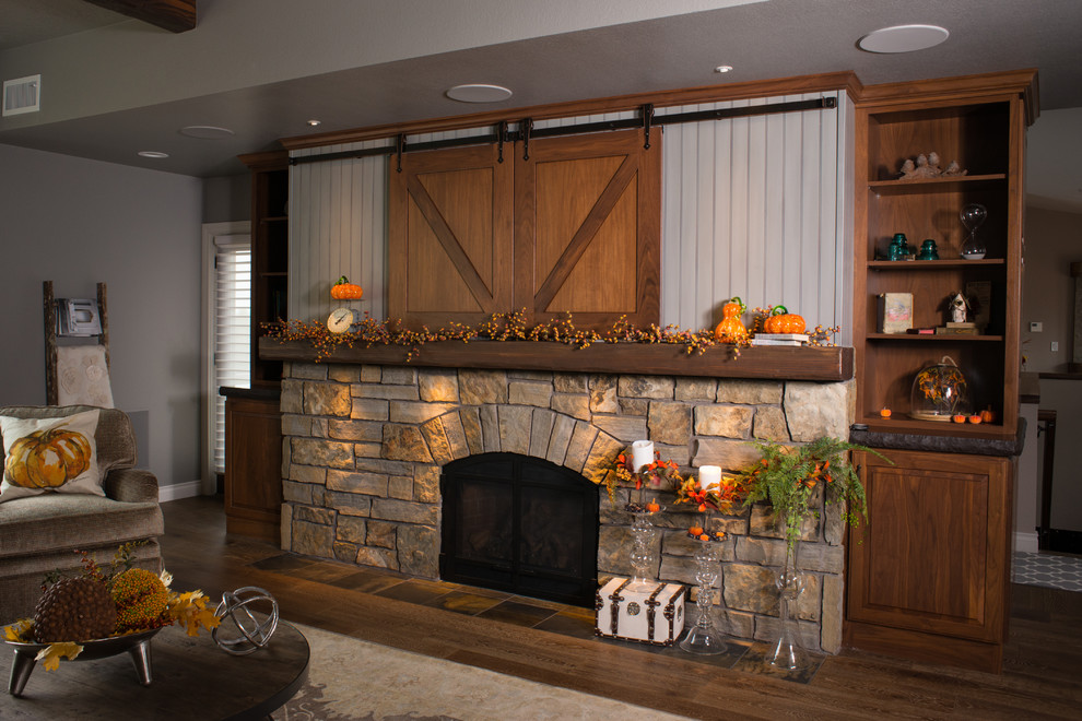 Inspiration for a large country open concept family room in Other with grey walls, dark hardwood floors, a standard fireplace, a stone fireplace surround, a built-in media wall and brown floor.