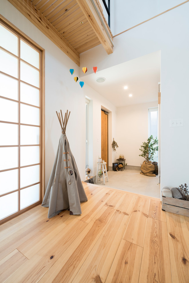 This is an example of an asian entry hall in Other with white walls, concrete floors, a single front door, a medium wood front door and grey floor.
