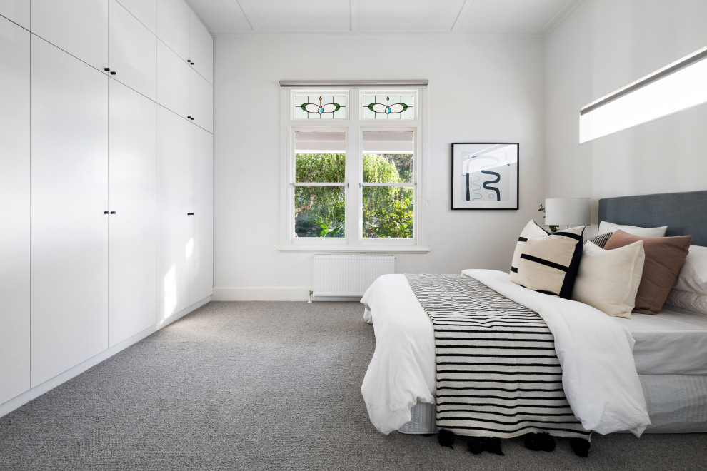 Large contemporary master bedroom in Melbourne with white walls, carpet and grey floor.