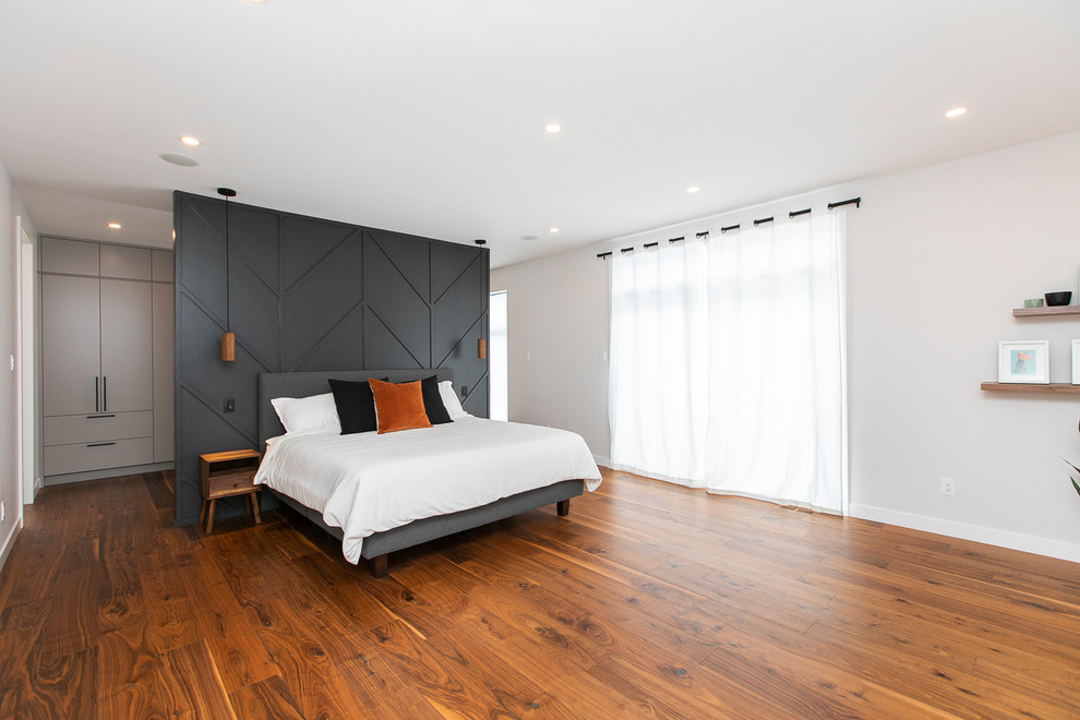Inspiration for a large contemporary master bedroom in Ottawa with grey walls, medium hardwood floors, no fireplace and brown floor.