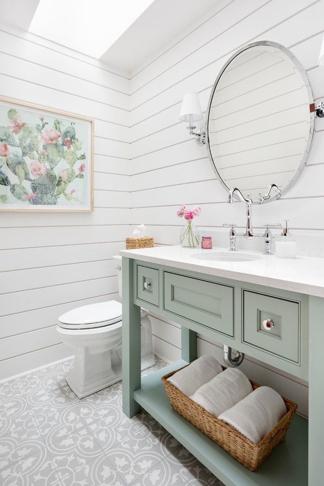Inspiration for a mid-sized country gray floor powder room remodel in Seattle with green cabinets, a two-piece toilet, white walls, an undermount sink, white countertops and a freestanding vanity
