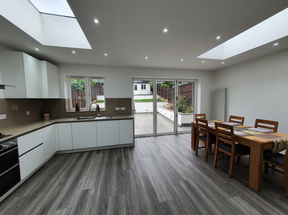 Aménagement d'une grande salle à manger ouverte sur la cuisine contemporaine avec un mur blanc, un sol en vinyl, un sol gris et éclairage.