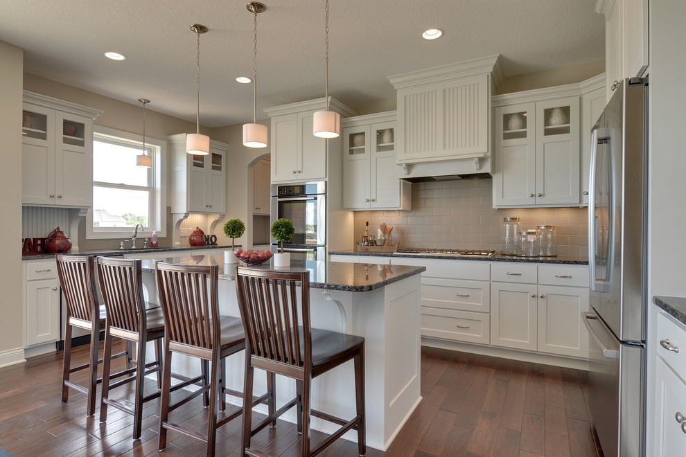 Large transitional u-shaped open plan kitchen in Minneapolis with an undermount sink, recessed-panel cabinets, white cabinets, granite benchtops, grey splashback, subway tile splashback, stainless steel appliances, medium hardwood floors and with island.