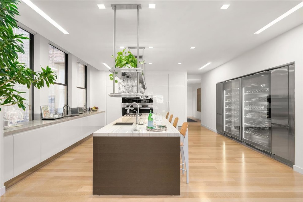 Design ideas for a modern kitchen with flat-panel cabinets, white cabinets, stainless steel appliances, with island, yellow floor, white benchtop and an undermount sink.