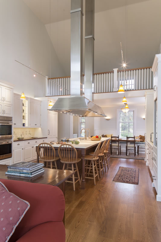 Open concept kitchen - huge traditional galley medium tone wood floor and brown floor open concept kitchen idea in Jacksonville with raised-panel cabinets, white cabinets, stainless steel appliances, an island, multicolored backsplash, an undermount sink, limestone countertops and porcelain backsplash
