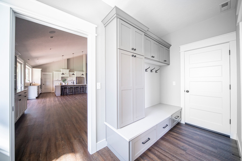 This is an example of a large transitional galley utility room in Portland with an undermount sink, shaker cabinets, grey cabinets, quartz benchtops, grey walls, medium hardwood floors, a side-by-side washer and dryer, brown floor and white benchtop.