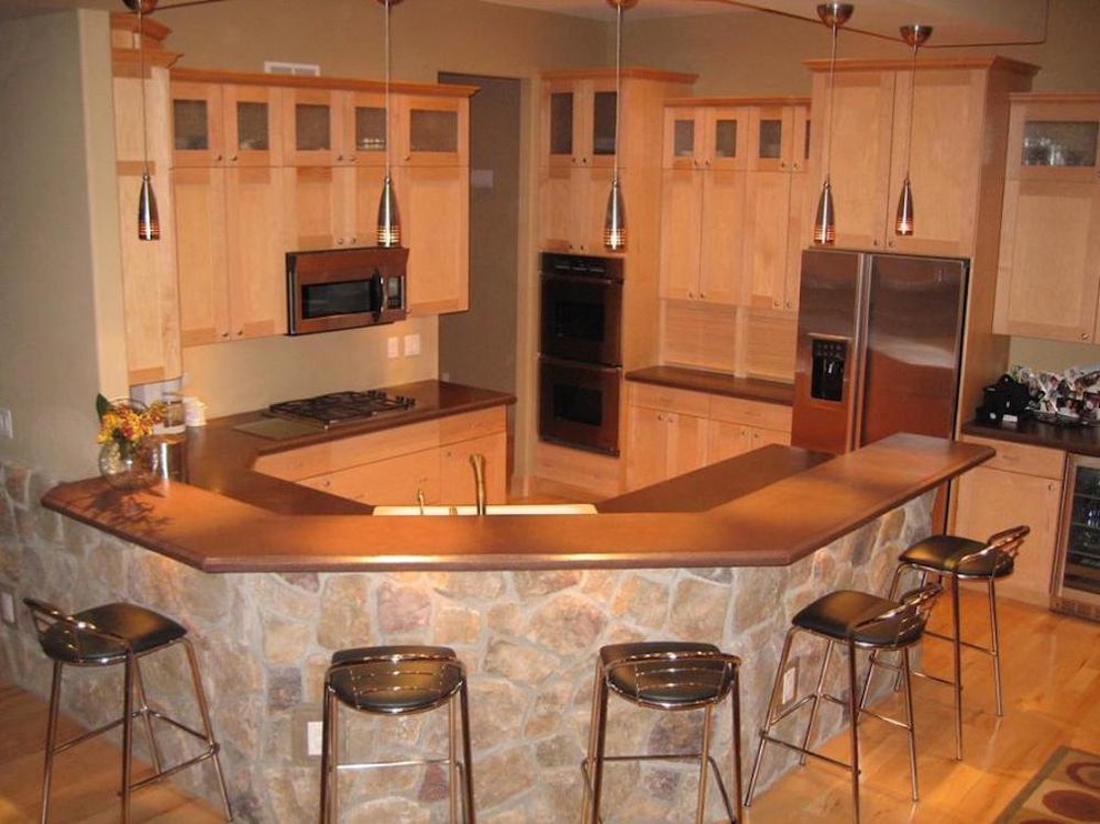 This is an example of a mid-sized contemporary single-wall eat-in kitchen in Cedar Rapids with an undermount sink, shaker cabinets, light wood cabinets, soapstone benchtops, stainless steel appliances, light hardwood floors and a peninsula.
