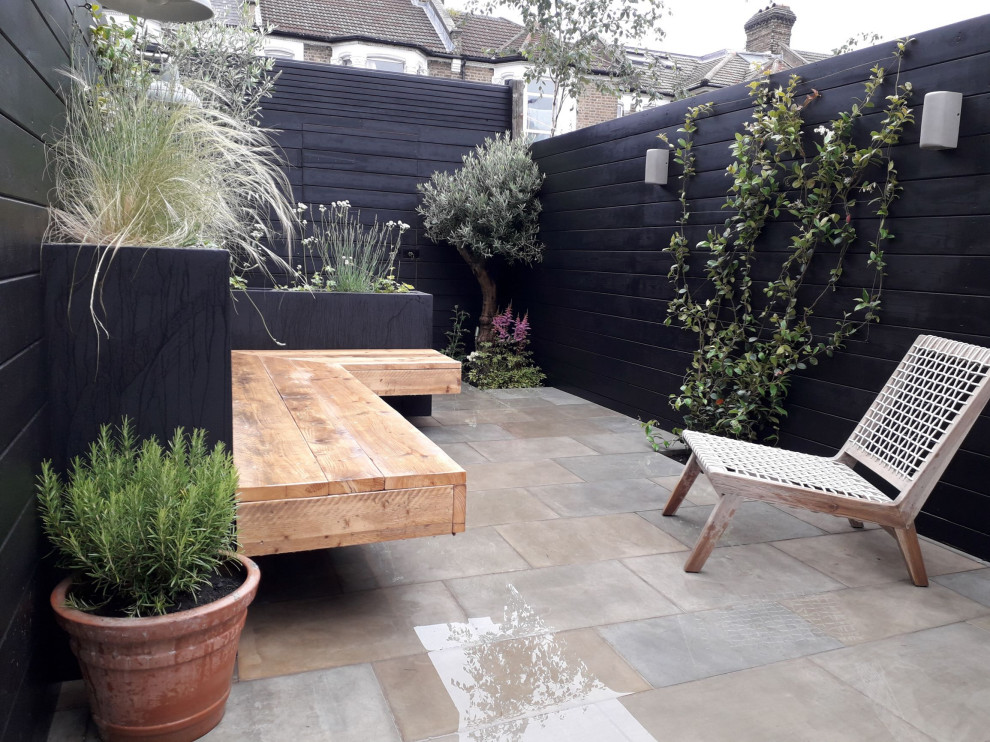 Photo of a small contemporary backyard partial sun formal garden for spring in London with with raised garden bed, natural stone pavers and a wood fence.