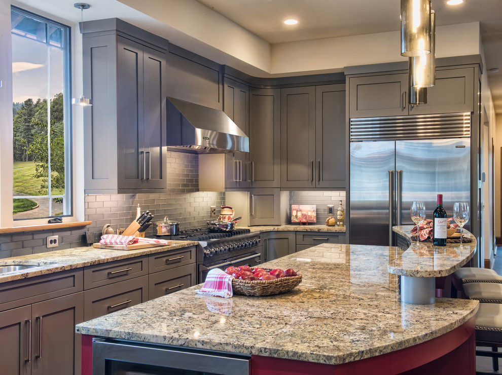 Example of a large transitional u-shaped limestone floor eat-in kitchen design with an undermount sink, shaker cabinets, gray cabinets, granite countertops, gray backsplash, glass tile backsplash, stainless steel appliances and an island