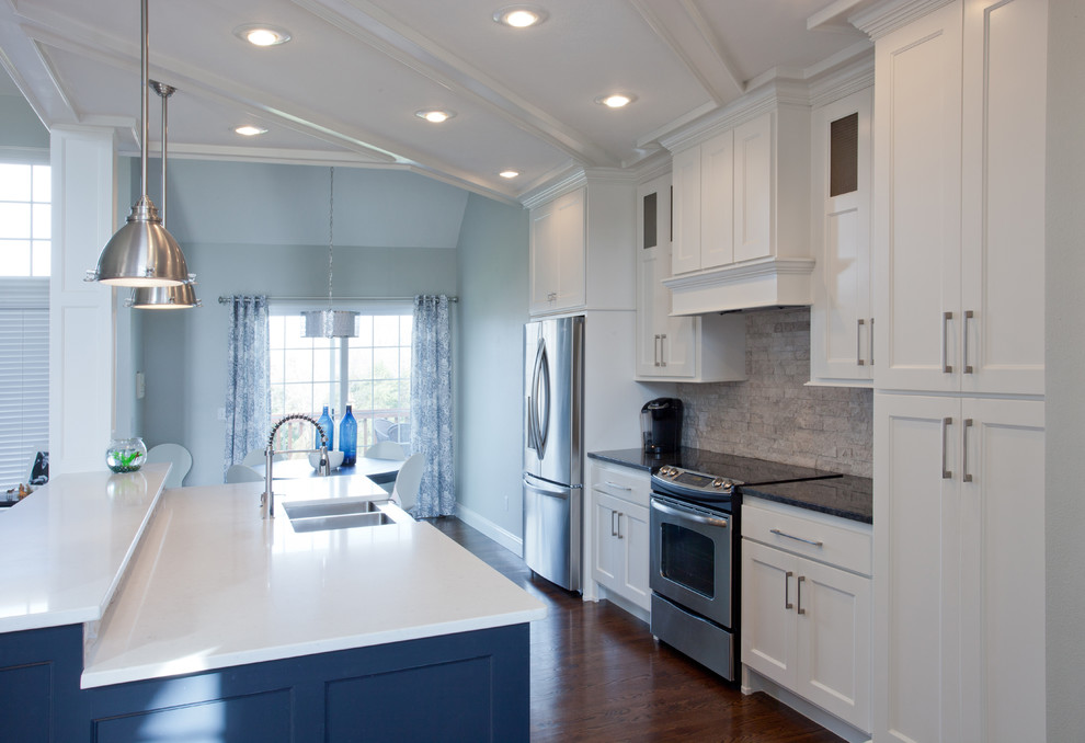 This is an example of a mid-sized traditional galley eat-in kitchen in St Louis with shaker cabinets, white cabinets, granite benchtops, white splashback, stone tile splashback, stainless steel appliances, dark hardwood floors, with island, a farmhouse sink and brown floor.