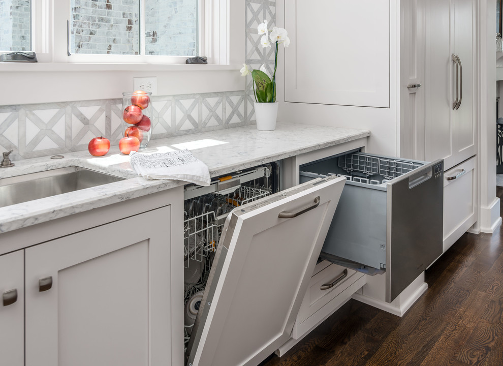 Example of a transitional l-shaped dark wood floor and brown floor open concept kitchen design in Nashville with an undermount sink, beaded inset cabinets, white cabinets, quartz countertops, white backsplash, stone tile backsplash, stainless steel appliances, an island and white countertops