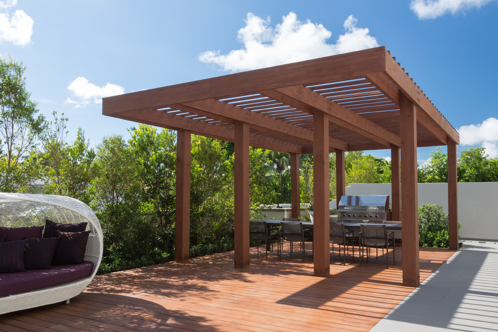 This is an example of a mid-sized contemporary backyard deck in Miami with a pergola.