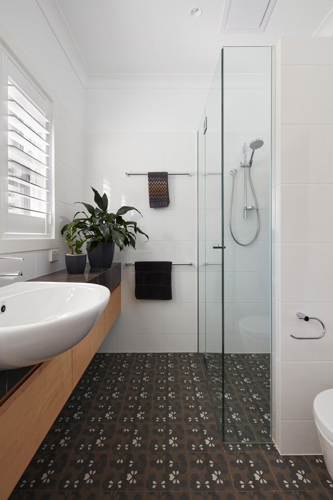Design ideas for a small contemporary 3/4 bathroom in Canberra - Queanbeyan with light wood cabinets, an alcove shower, a one-piece toilet, white tile, ceramic tile, white walls, cement tiles, a drop-in sink, marble benchtops, brown floor, a hinged shower door, black benchtops and flat-panel cabinets.