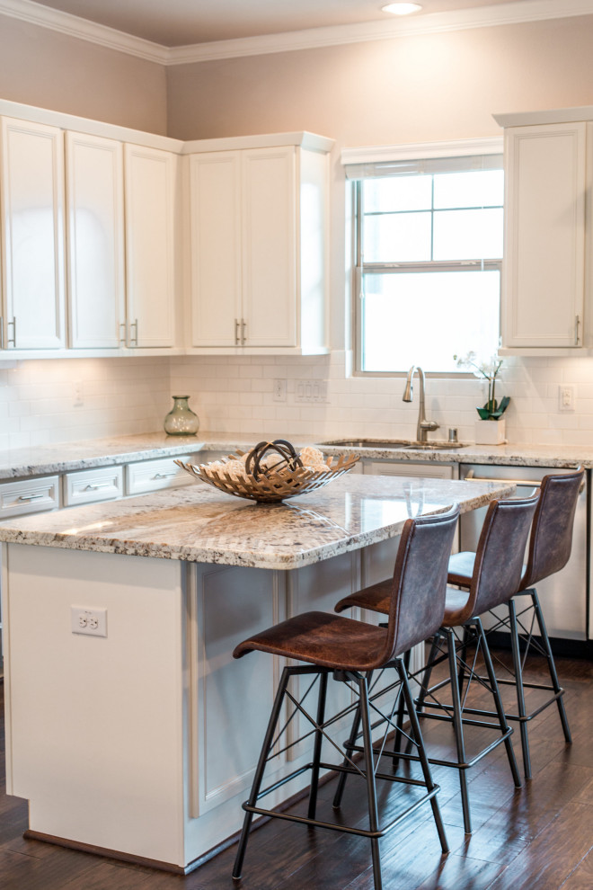 Example of a mid-sized transitional galley medium tone wood floor enclosed kitchen design in Austin with an undermount sink, shaker cabinets, white cabinets, granite countertops, stainless steel appliances, an island and white countertops