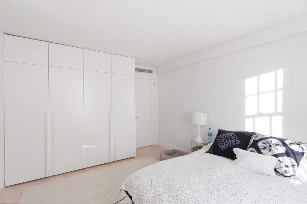 Photo of a scandinavian bedroom in New York with white walls and light hardwood floors.