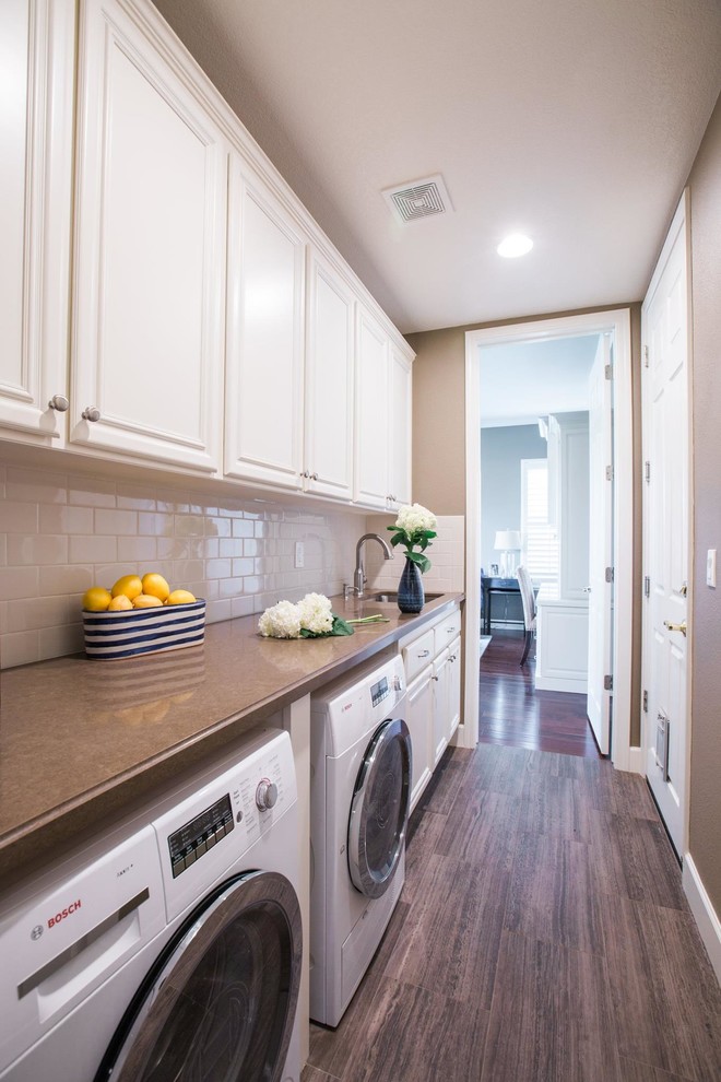Mid-sized transitional single-wall laundry room in San Francisco with an undermount sink, raised-panel cabinets, beige walls, vinyl floors and a side-by-side washer and dryer.