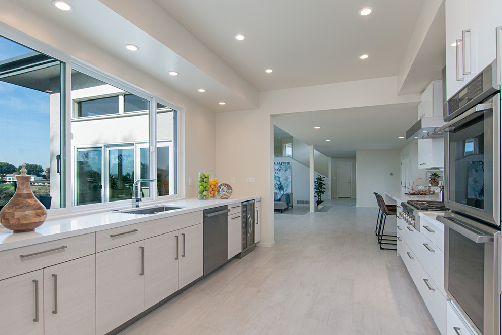 Design ideas for a large contemporary galley eat-in kitchen in San Diego with an undermount sink, flat-panel cabinets, white cabinets, quartz benchtops, stainless steel appliances and porcelain floors.