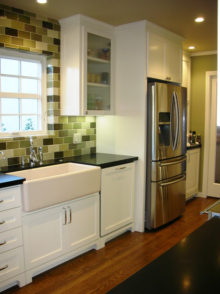 Photo of a small traditional galley separate kitchen in Sacramento with a farmhouse sink, shaker cabinets, white cabinets, solid surface benchtops, green splashback, porcelain splashback, stainless steel appliances and medium hardwood floors.